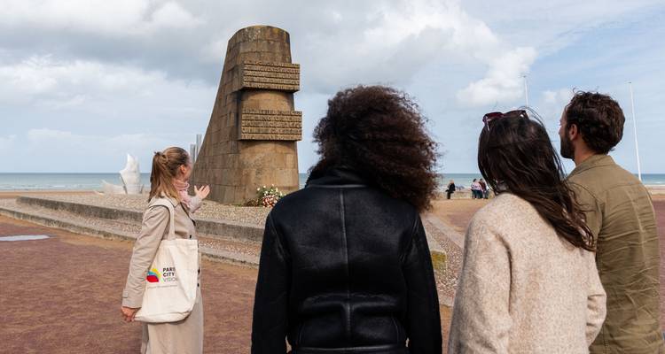 Des gens observant un monument sur une plage.