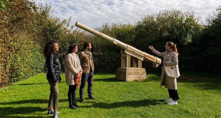 Groupe de personnes avec un guide debout près d'un canon historique.