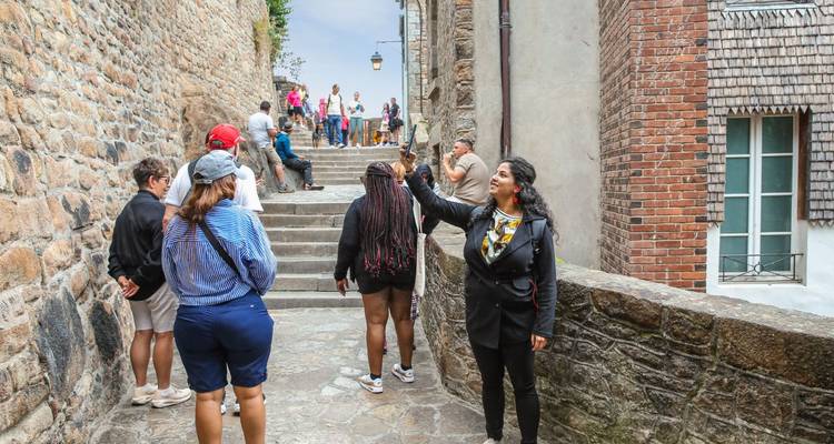 Toeristen die door een smalle kasseienstraat lopen.