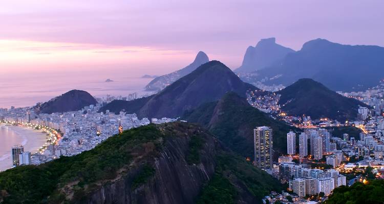 Aerial view of Rio de Janeiro with mountains and coastline at sunset.