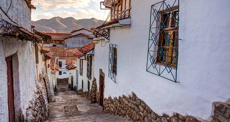 Ruelle étroite en pierre avec maisons blanchies à la chaux et toits de tuiles rouges dans les collines de Cusco