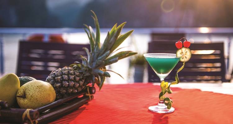 A refreshing cocktail and tropical fruits with a scenic water background.