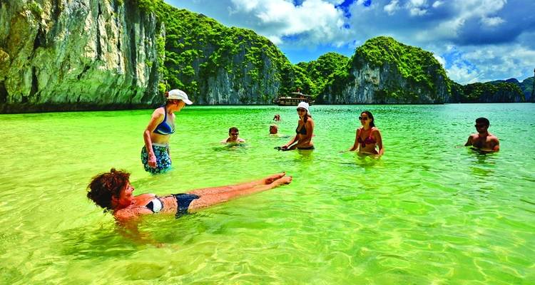 People enjoying a swim in a picturesque bay with limestone cliffs.