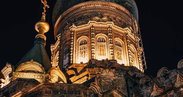 St. Sophia Cathedral in Harbin illuminated warmly against the dark night sky.