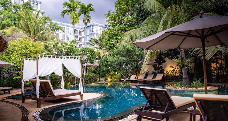Outdoor pool with cabanas surrounded by lush greenery.