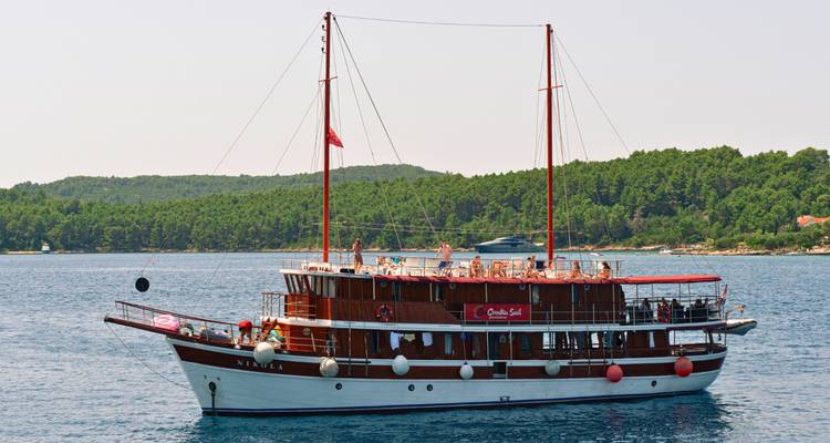 Un velero de madera en el agua con personas en cubierta.