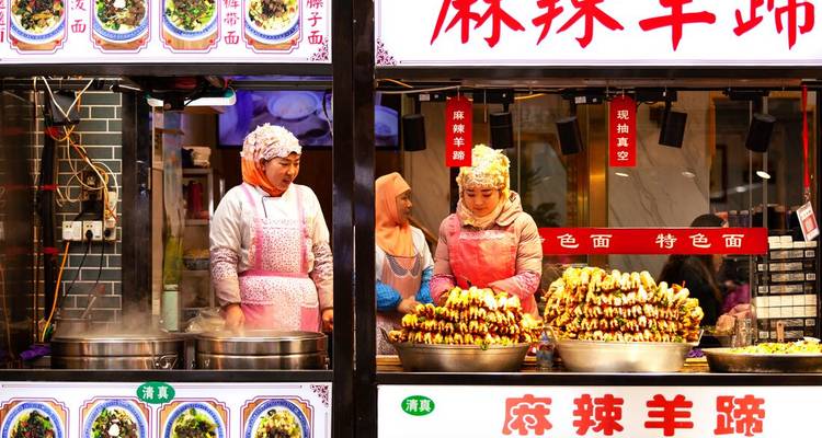 Un puesto de comida vibrante en la Calle Musulmana de Xi'an con vendedores y enormes pinchos de carne asada.