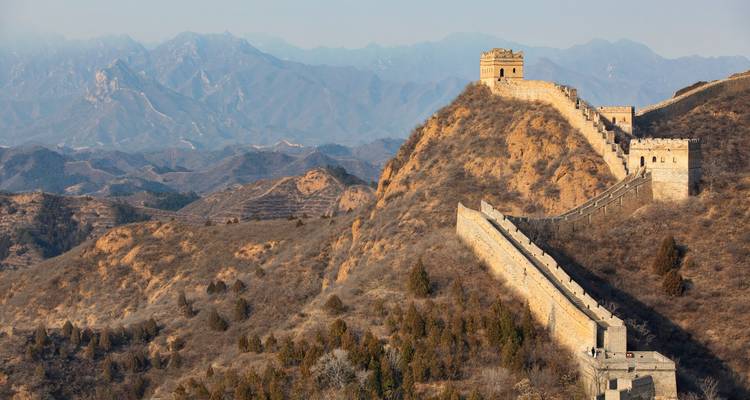 Sección de la Gran Muralla China serpentando sobre escarpadas crestas montañosas bajo cielos despejados.