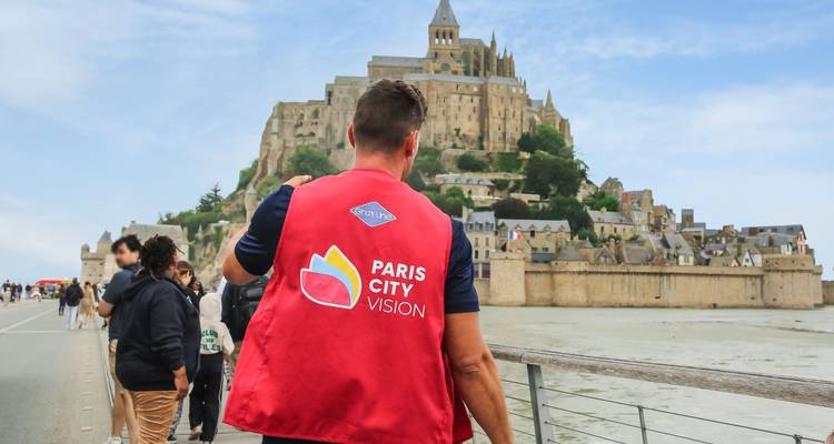 Een persoon die een rood vest draagt en naar Mont Saint-Michel kijkt.