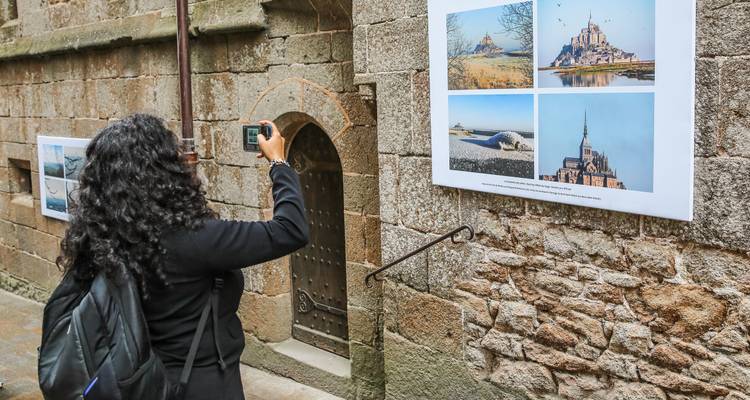 Fotograaf die foto's maakt van Mont Saint-Michel die aan een muur hangen.