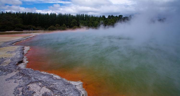 Vibrant hot spring with colored mineral deposits and steam.