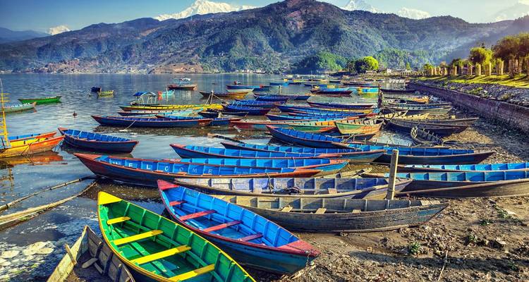 Colorful boats on Phewa Lake with mountains around.