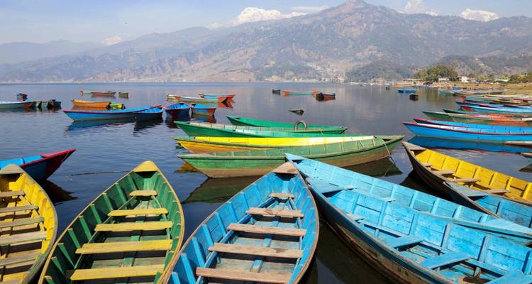 Colorful boats floating on Phewa Lake with mountain backdrop.