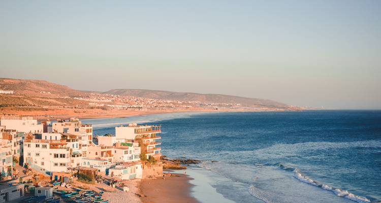 Küstenstadt mit weiß getünchten Gebäuden entlang eines langen Sandstrandes zur goldenen Stunde