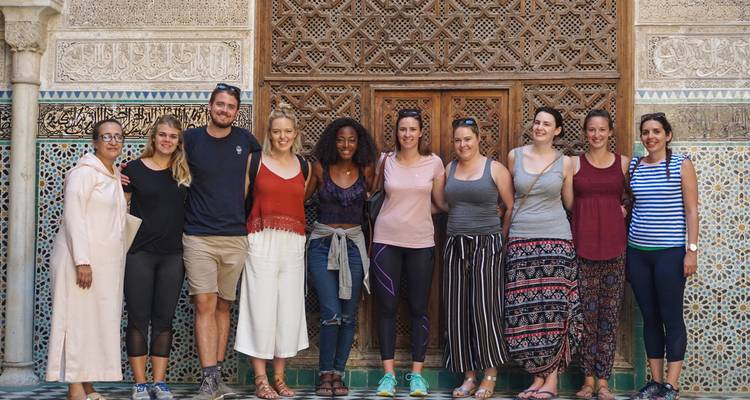 Gruppe von Reisenden, die vor einem kunstvoll gefliesten marokkanischen Türeingang posieren