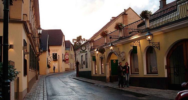 Charmante rue étroite avec des maisons de ville aux couleurs pastel, des balcons en fer forgé et des lampadaires du soir, banlieue de Vienne.