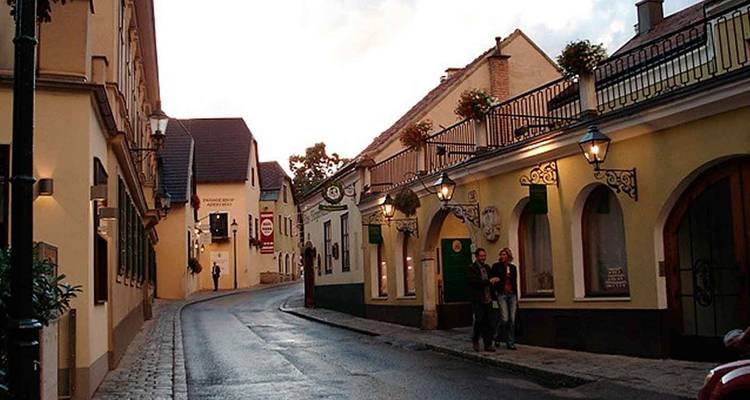 Narrow cobblestone lane lined with quaint pastel houses, wrought-iron balconies and lanterns at dusk.