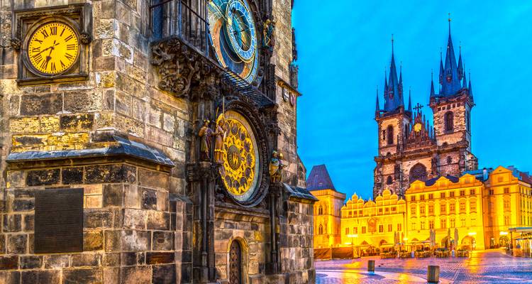 Abendliche Blaue-Stunde-Szene von Prags Astronomischer Uhr und der beleuchteten Teynkirche.