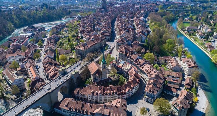 Vue aérienne d'une péninsule de vieille ville étroite et sinueuse traversée par des ponts et bordée par une rivière d'un bleu éclatant.
