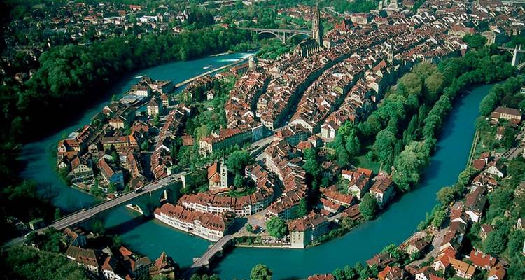 Rivière sinueuse embrassant une vieille ville européenne médiévale remplie de toits de tuiles rouges vue d'en haut.