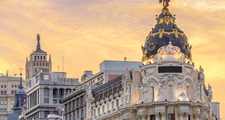 Detalle de la cúpula del Edificio Metrópolis de Madrid brillando bajo la cálida luz del atardecer.