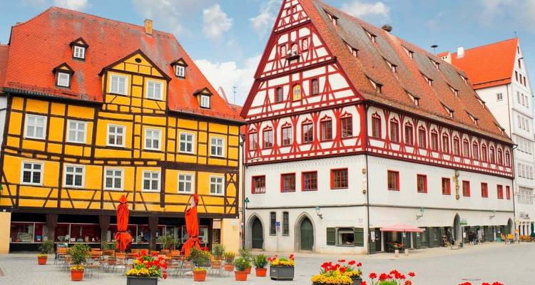 Charmanter mittelalterlicher Platz mit bunten Fachwerkhäusern und Café-Tischen im Freien