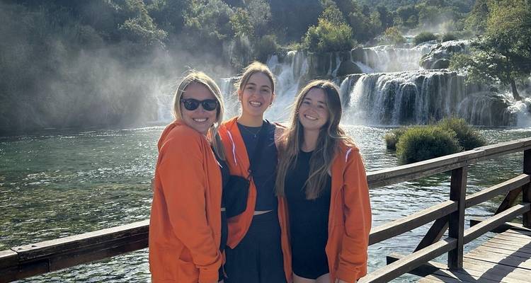 Trois femmes devant une cascade dans un parc.