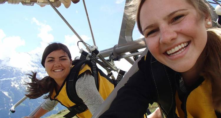 Menschen, die beim Paragliding lächeln, mit Bergen im Hintergrund.