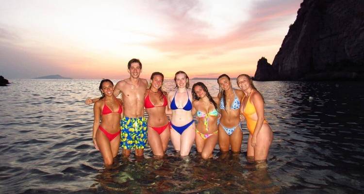 Groupe d'amis en maillots de bain profitant d'une baignade au coucher du soleil.