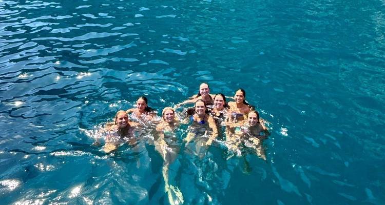 Groupe de personnes nageant dans une eau bleue claire.