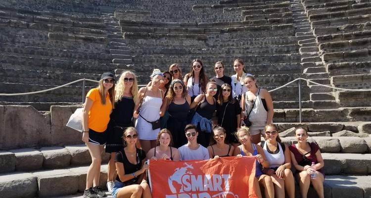 Groupe de personnes tenant une bannière de visite guidée dans un amphithéâtre antique.