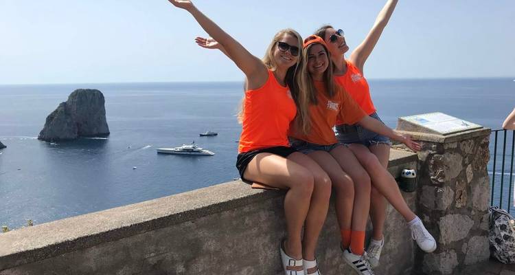 Tres personas posando con vista al mar y un yate al fondo.