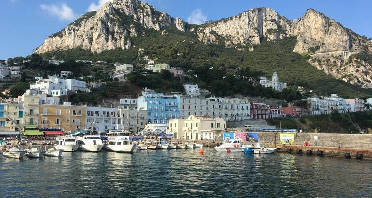 Pueblo pintoresco con barcos amarrados en el puerto y montañas detrás.