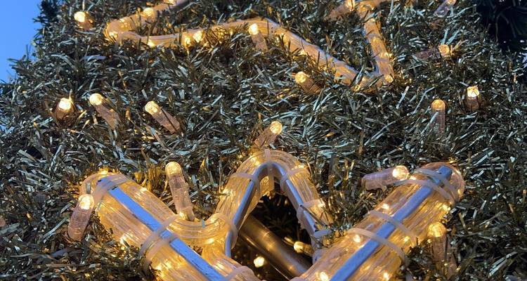 Twinkling golden fairy lights intertwine in tinsel creating a festive close-up pattern.