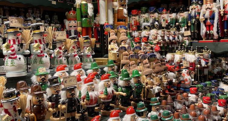Colorful rows of wooden nutcracker figurines and festive toys crowd a Christmas market stall.