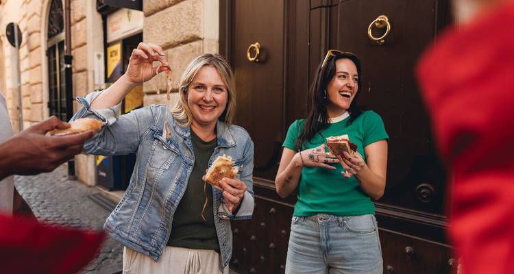 Reisende genießen frisch zubereitete Pizzastücke auf einer lebhaften römischen Straße und teilen Lachen sowie lokale Geschmacksrichtungen.