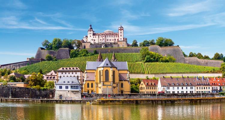La forteresse de Marienberg, perchée au sommet d'une colline, s'élève au-dessus des vignobles en terrasses et des bâtiments colorés en bordure de rivière à Würzburg