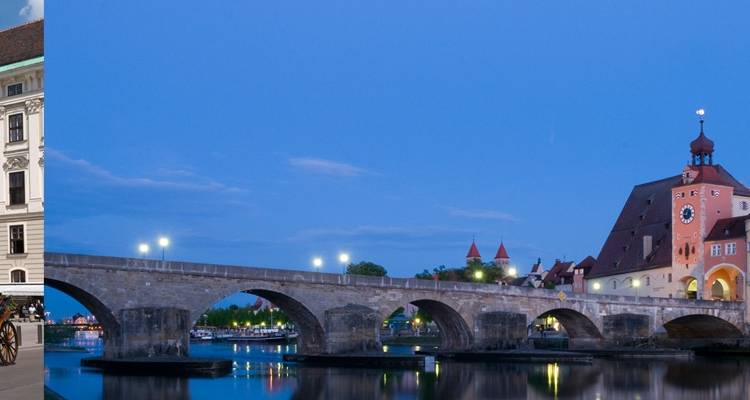 Vue crépusculaire du pont de pierre médiéval de Ratisbonne et des bâtiments riverains reflétés dans l'eau calme