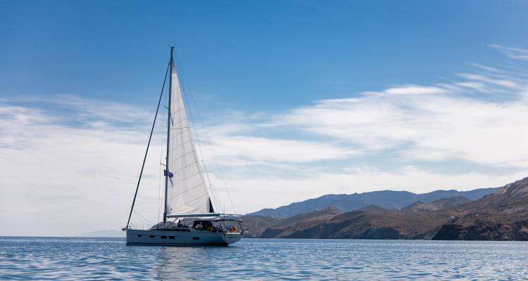 Voilier sur une mer calme avec des collines en arrière-plan.