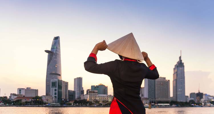 Persona en atuendo tradicional con el horizonte de la Ciudad de Ho Chi Minh.