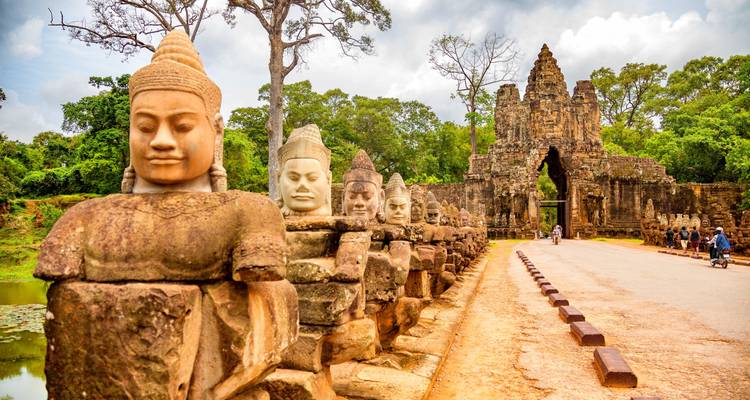 Entrada de Angkor Thom con estatuas de piedra y turistas.