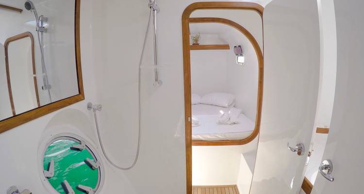Baño en suite del barco con mucha luz que da a un acogedor camarote