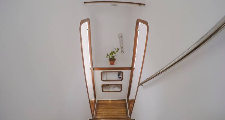 Escaleras de madera y paredes blancas minimalistas en un pasillo de yate