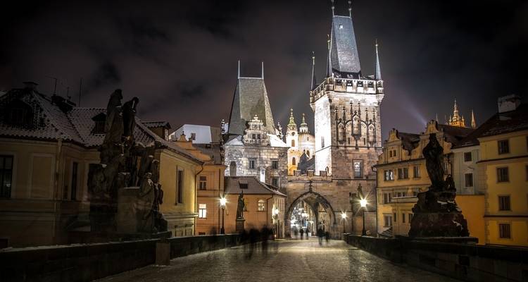 Charles Bridge in Prague at night with historical towers.