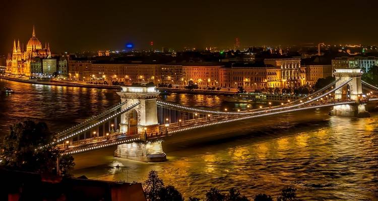 Chain Bridge and Parliament building illuminated at night in Budapest.