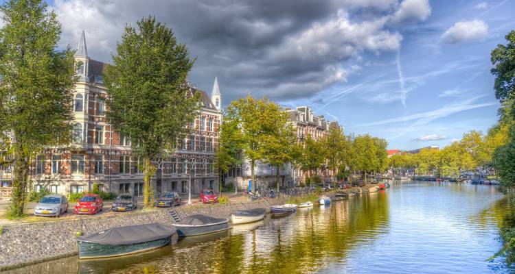Canal tranquilo en Ámsterdam con árboles y edificios residenciales.