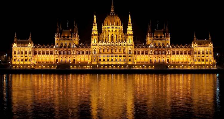 El Parlamento húngaro iluminado por la noche, reflejándose en el Danubio.