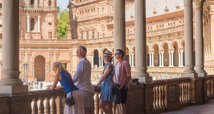 Travellers lean on balustrade admiring the ornate arches of Plaza de España.