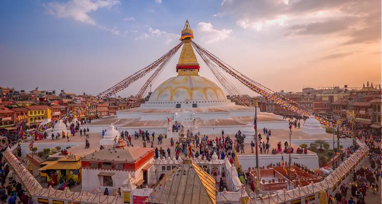 Weitläufige Ansicht der kreisförmigen Boudhanath Stupa, umgeben von Pilgern und farbenfrohen Gebetsfahnenlinien.