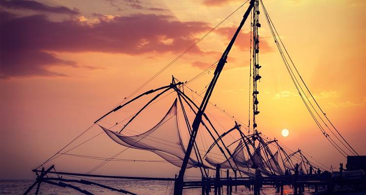 Traditionelle chinesische Fischernetze als Silhouetten vor einem Sonnenuntergang.